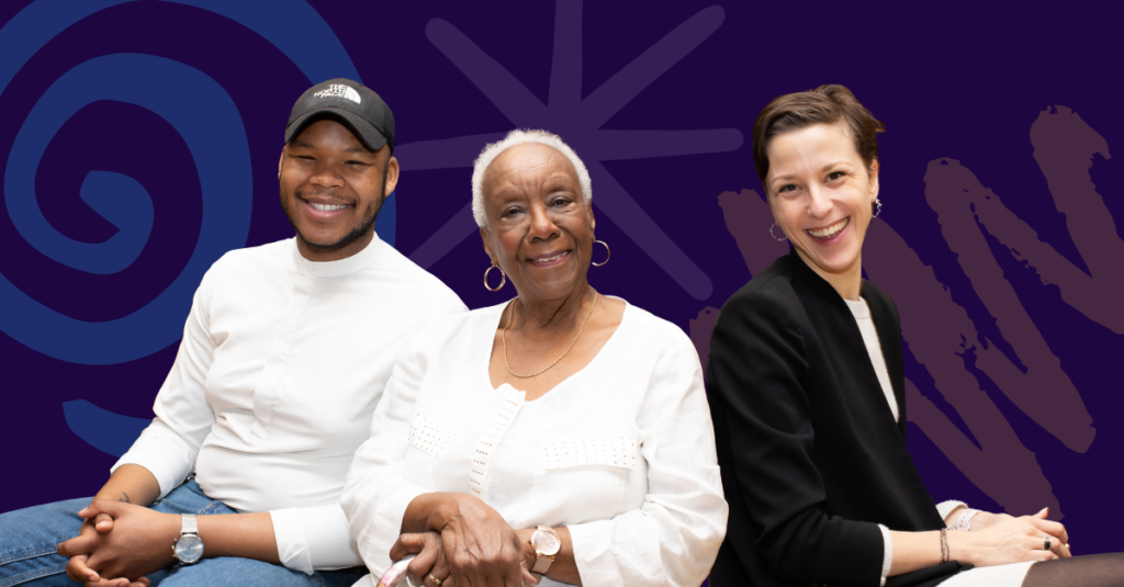 Three training participants smile at the camera against a purple backdrop