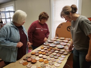 Three participants admire pottery pieces on a table.