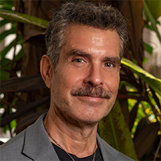Headshot of Ben Prayz. He has dark short hair and dark eyes. He has a mustache and is smiling.