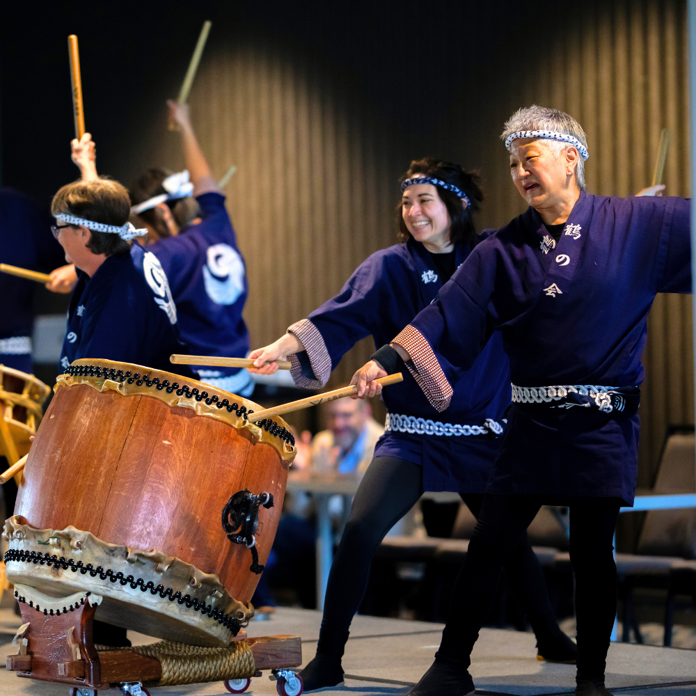 A group of young and older people drumming.