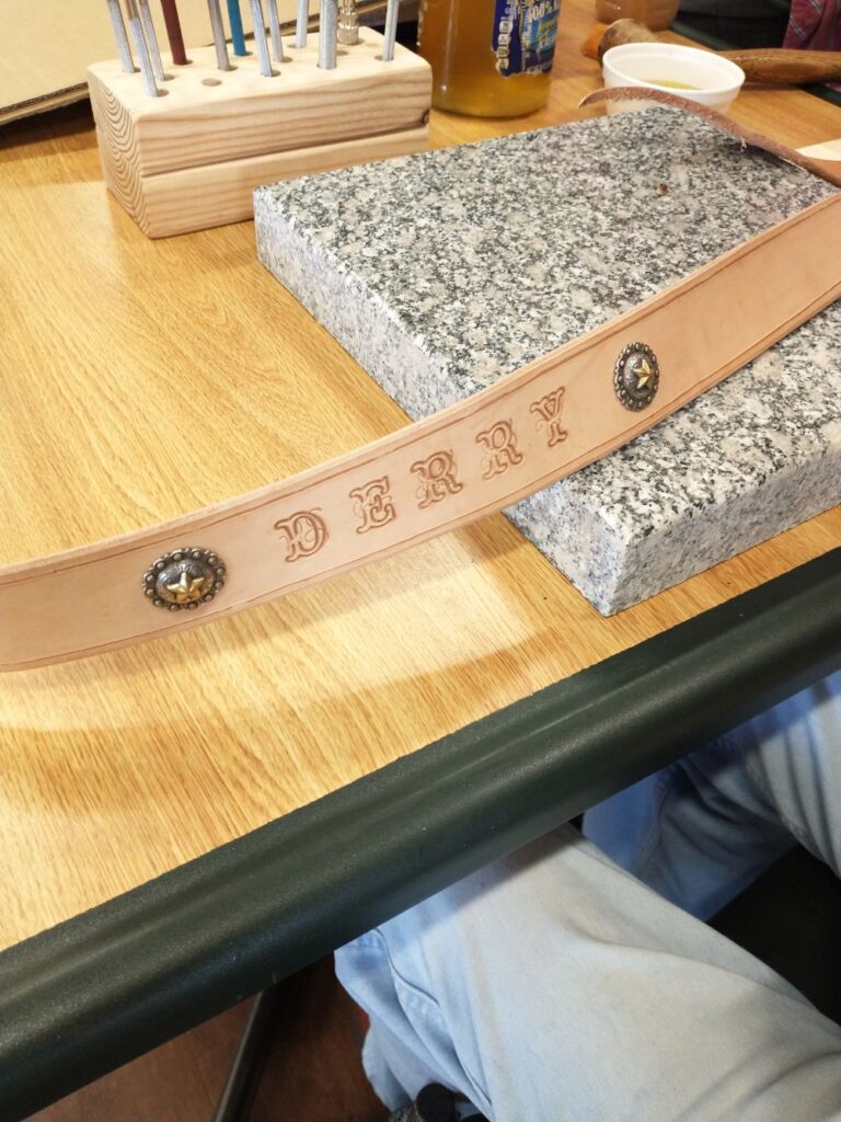 PIcture of a leather belt with the name "Derry" engraved on it.