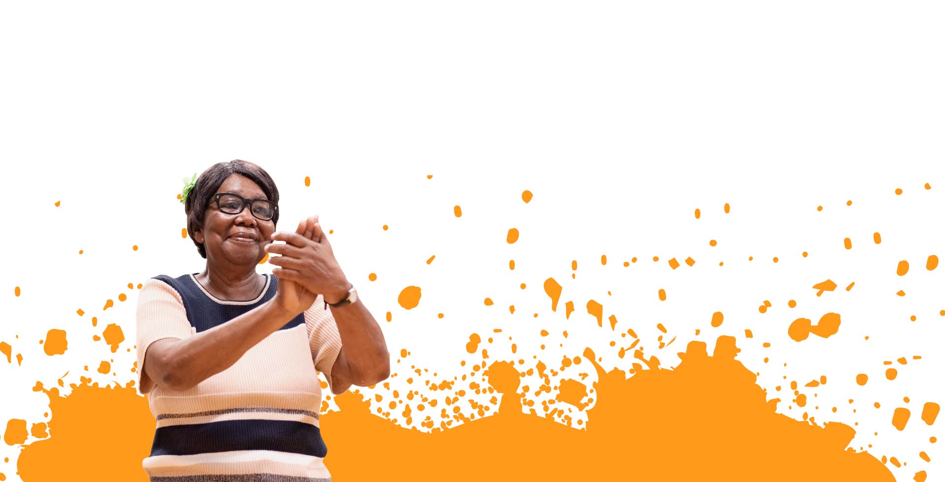 An older woman claps and smiles. Orange paint splatter surrounds her.