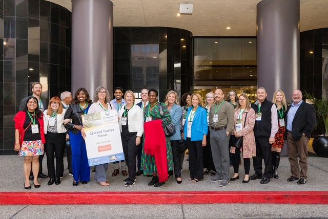 A larrge group photo of arts and health leaders standing outside a building and smiling.