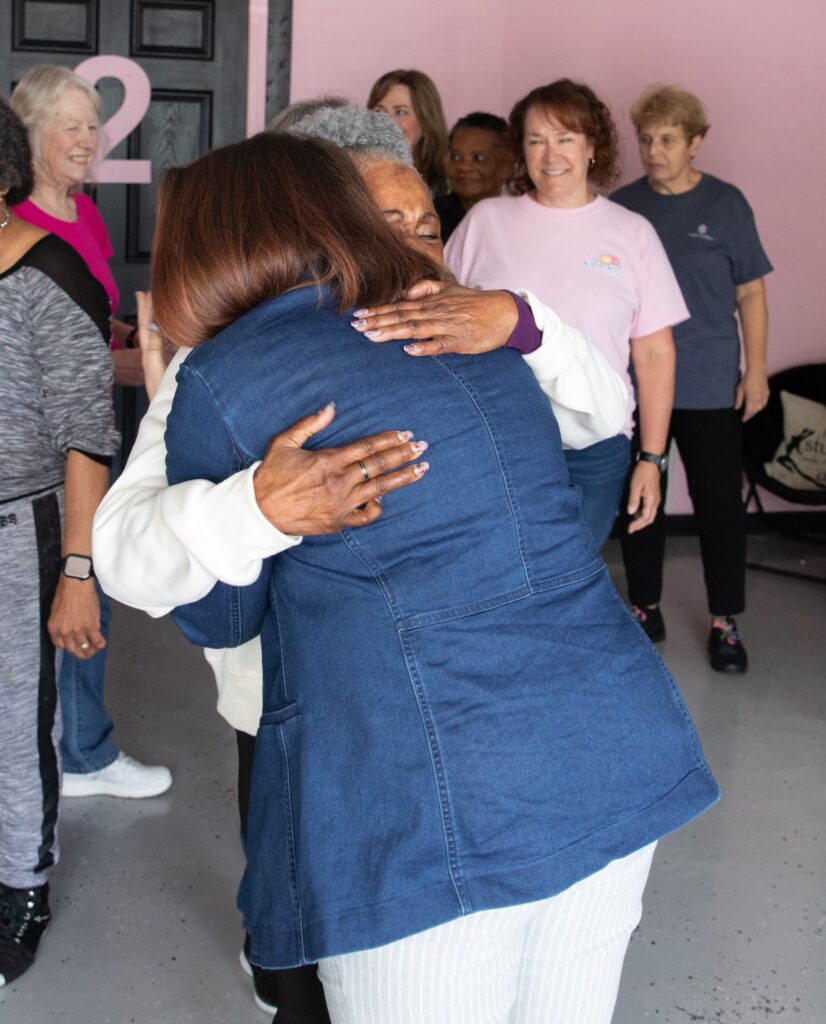 Liza Cucco hugs an older adult student during a dance program.