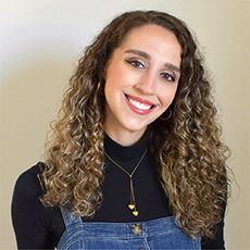 Headshot of Jacqueline DuMont. She has light brown curly hair and brown eyes. She is smiling.