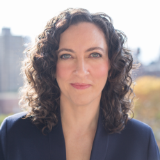 Headshot of Julie Kline. She has dark wavy hair and hazel eyes. She is smiling.
