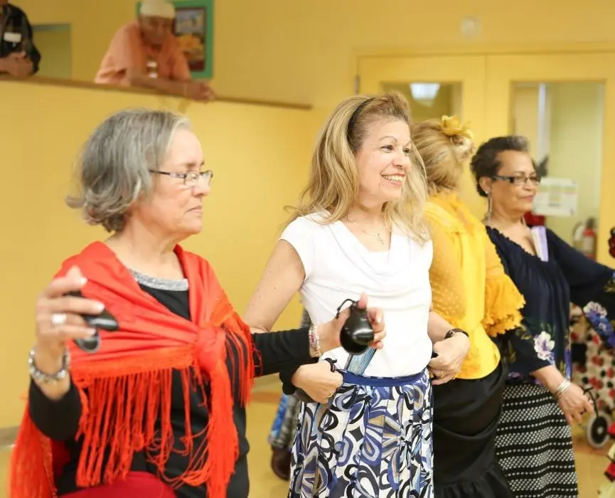 A group of older women dance in a line.