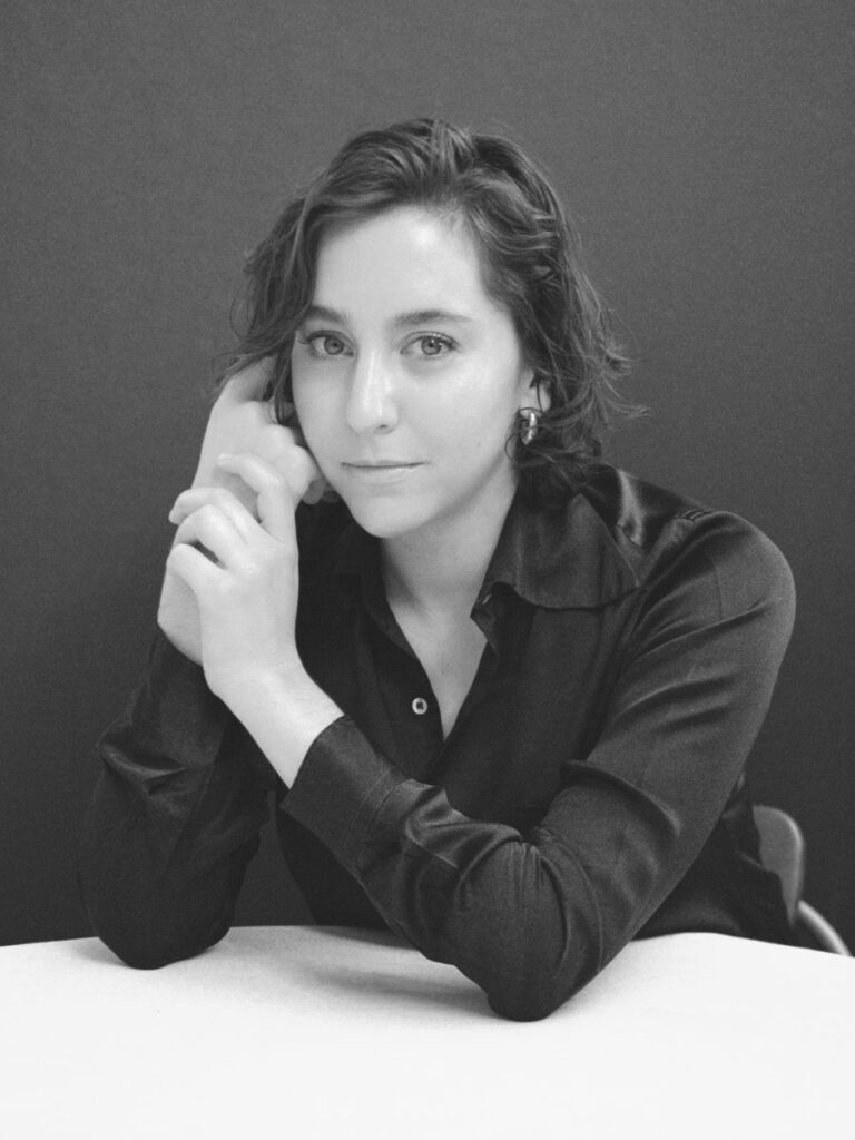 A black and white headshot of Sarah Friedland, writer and director of the film, "Familiar Touch." She has short, brown hair and is wearing a dark blouse.