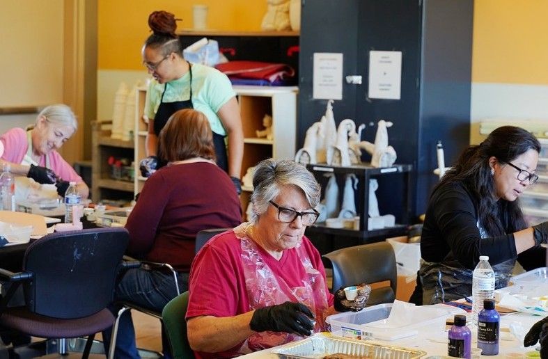 A group of older adult participants paint at tables.