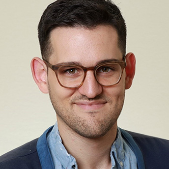 Headshot of Vinny Mraz. He has short, dark brown hair and brown eyes. He is wearing brown-framed glasses and is smiling.