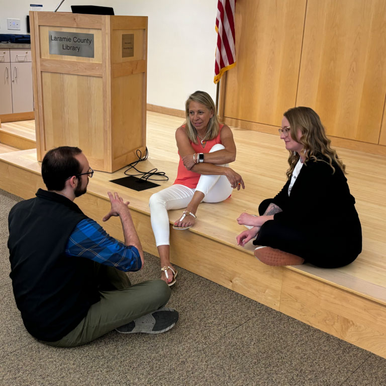 A group of middle-aged adults sit in a circle and talk to each other.