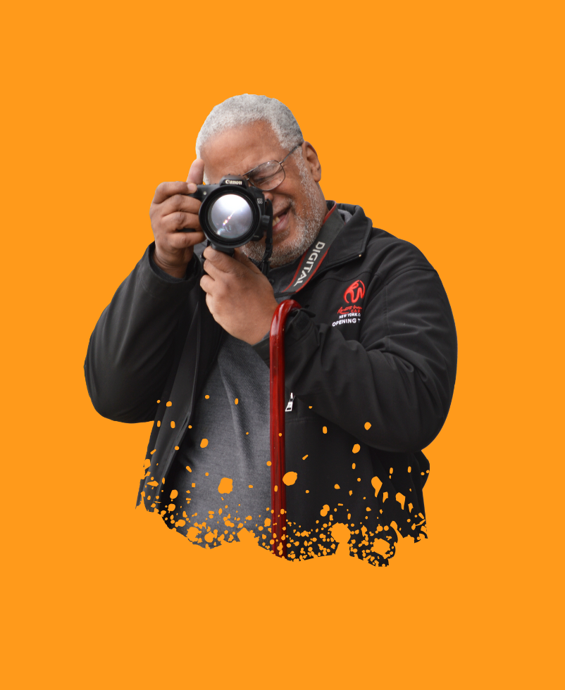 An older adult man takes a picture with a photography camera.