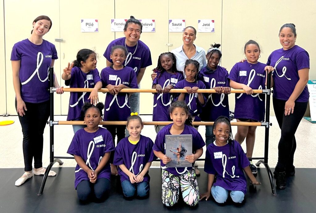 A group of kids pose at a ballet beam with their instructors.